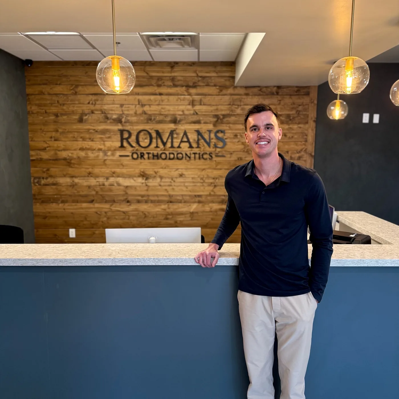 Dr. Nicholas Romans at the front desk of Romans Orthodontics in Anthem, Arizona